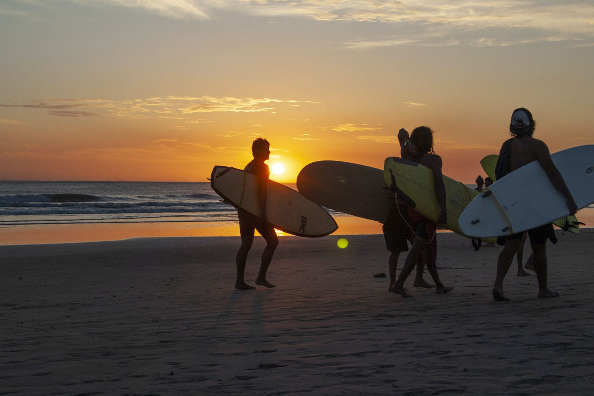 Grupo de amigos caminhando em uma praia da Costa Rica ao pôr do sol