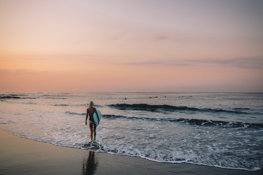 girl walking into the water at a tropical surf beach
