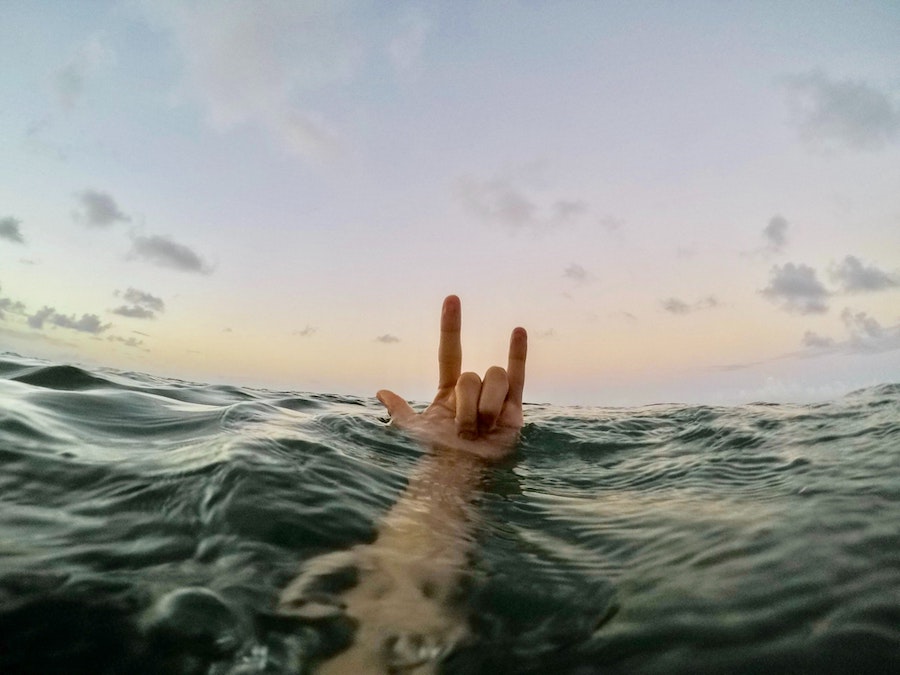 man throwing a shaka while in the water