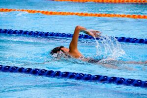Persons swimming in a pool, one of the best exercises for surfing