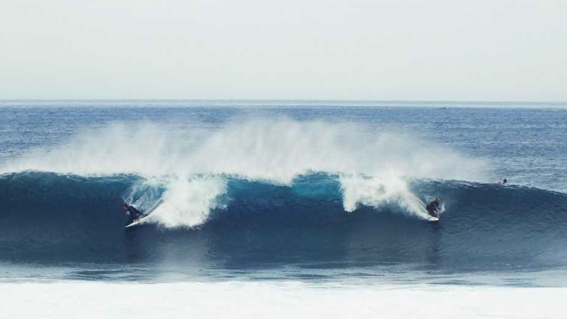 Two surfers riding the same wave, following the surfing etiquette