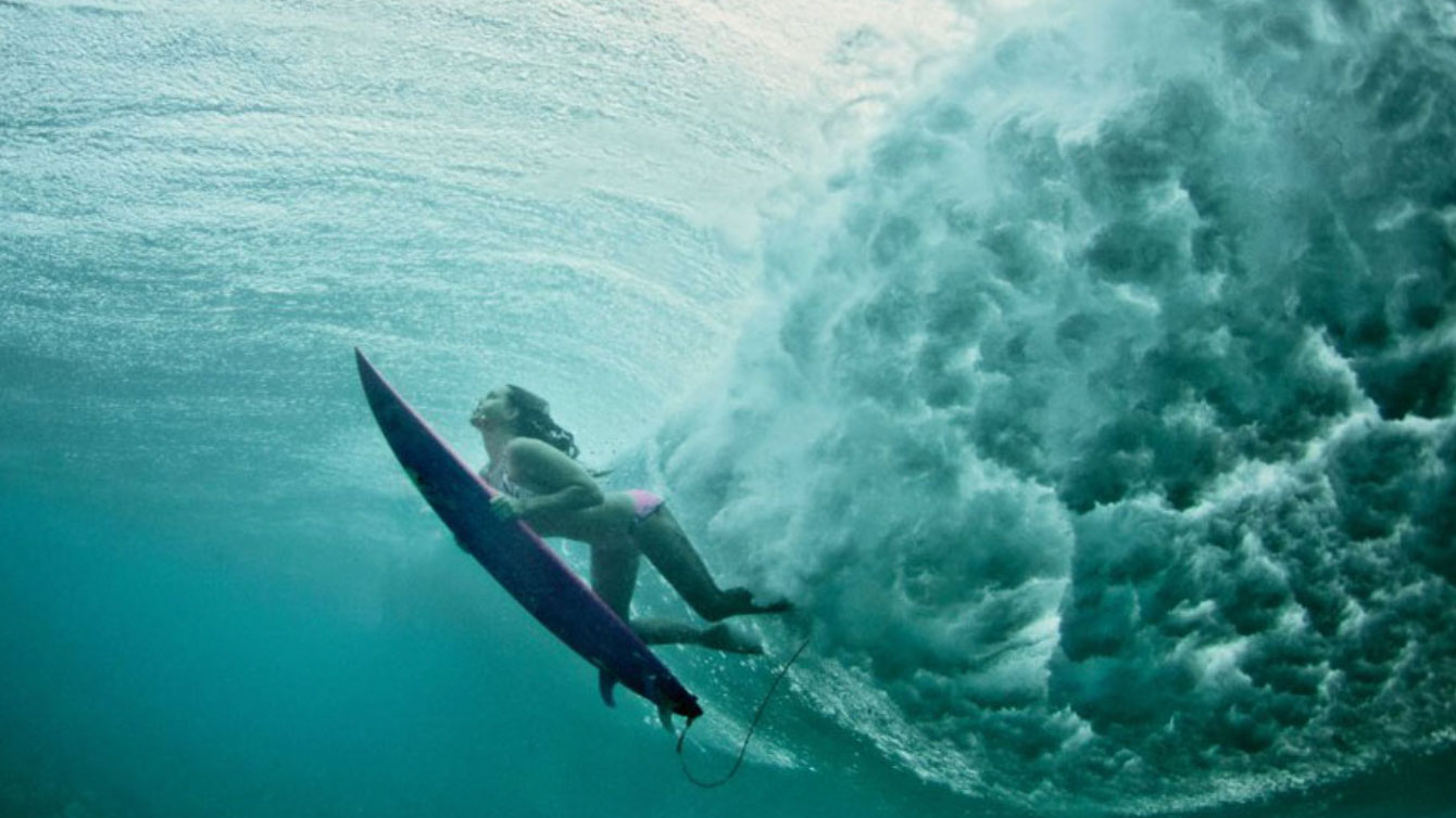 A surfer duck diving under a wave