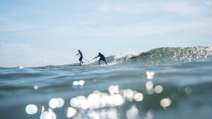 A surfer gets dropped-in by a paddle boarder