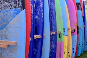 rack of colorful foam surfboards to demonstrate different boards and different prices of surfboards
